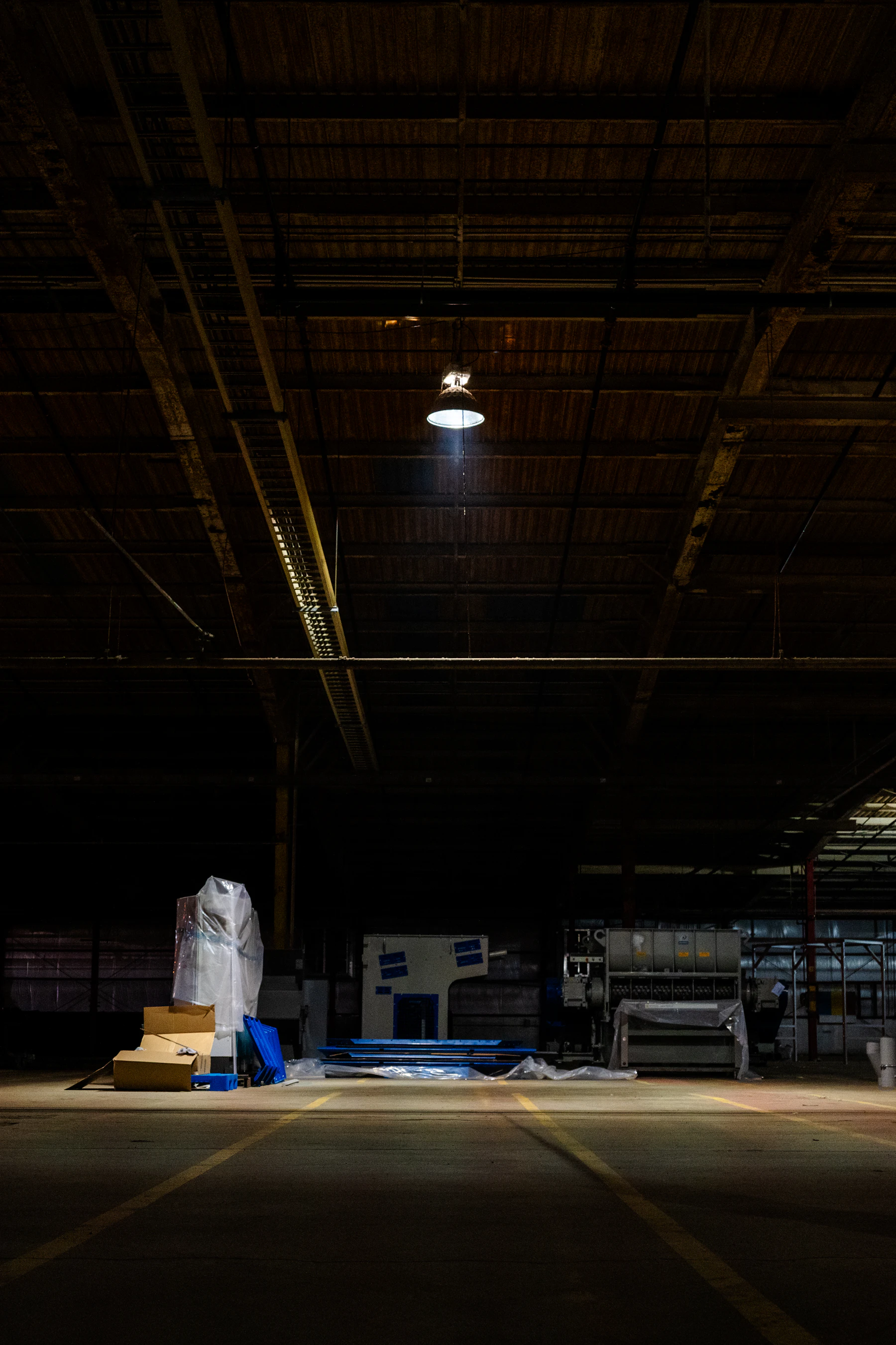 Industrial warehouse floor beneath a high roof and overhead work light